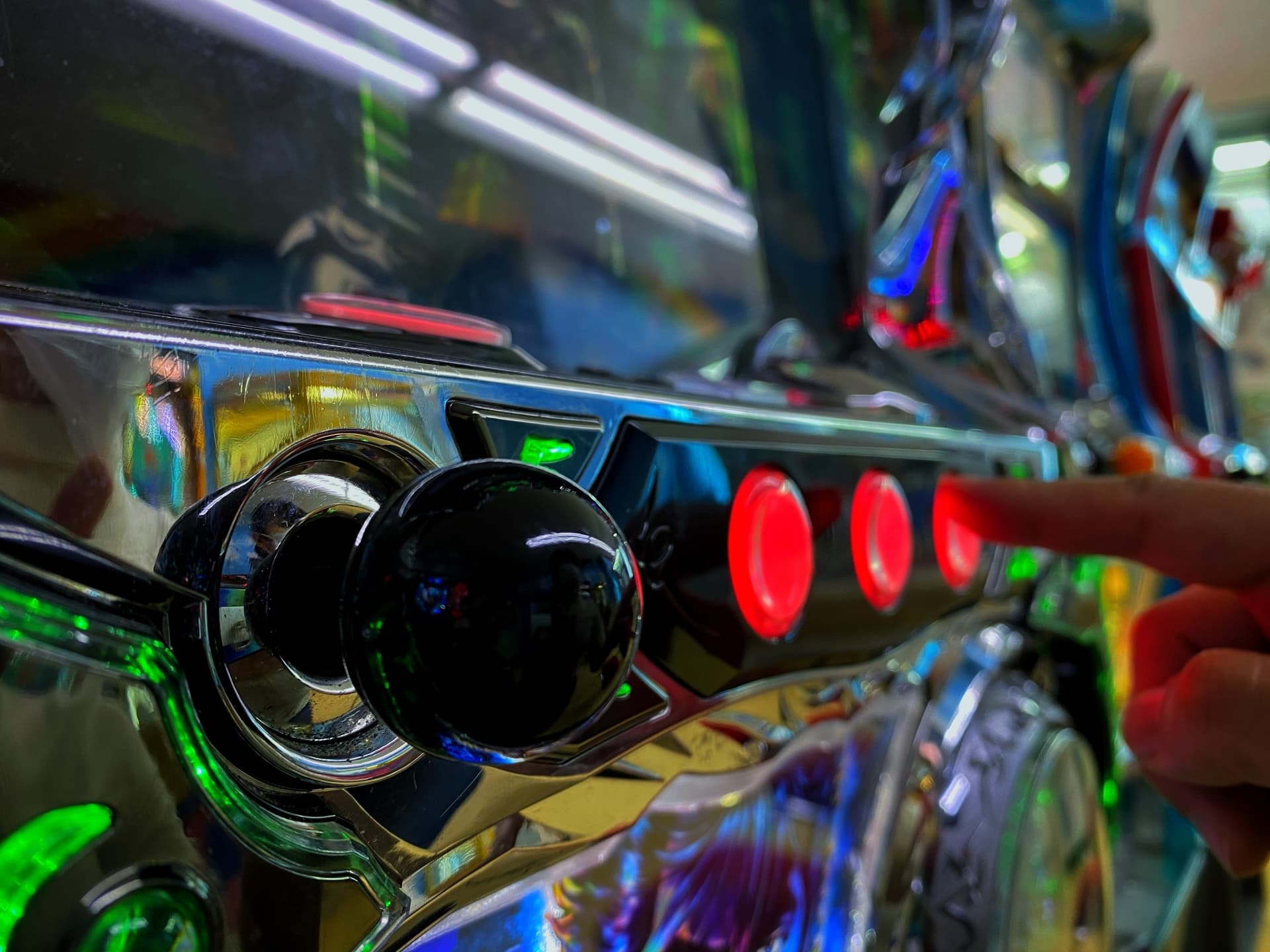 Close-up of a player pressing illuminated buttons on a pachinko machine.